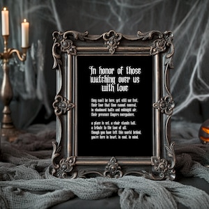 May include: A black framed print with a white background and a poem about remembering those who have passed away. The poem reads, "In honor of those watching over us with love. They can't be here, yet still we feel, their love that time cannot conceal. In shadowed halls and midnight air, their presence lingers everywhere. A place is set, a chair stands full, a tribute to the love of all. Though you have left this world behind, you're here in heart, in soul, in mind."