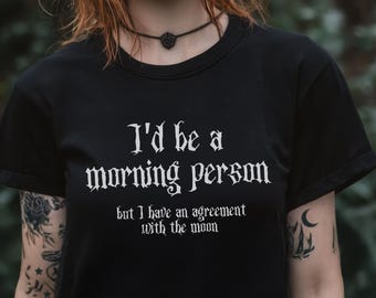 May include: Black t-shirt with white text that reads "I'd be a morning person but I have an agreement with the moon."