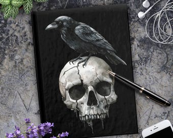 May include: A black crow perched on top of a white human skull with a cracked surface. The crow is facing left and the skull is facing forward. The background is black.