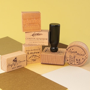 Pu&ograve; includere: Un set di timbri in legno con vari disegni. I timbri presentano testo come "Hayley Marion EST. 2022", "Gordon Renfrew 1223 Marvella Cir Rockledge, PA 65498", "From the library of Andrew", e "Elizabeth Mitchell".