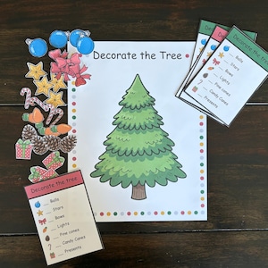 Puede incluir: Un juego de actividades navideñas con una ilustración de un árbol verde y el texto "Decorate the Tree". Incluye recortes de adornos, estrellas, lazos, luces, piñas, bastones de caramelo y regalos.