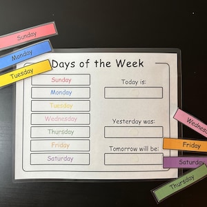 Può includere: Un grafico bianco laminato con il titolo "Giorni della settimana" e un elenco dei giorni della settimana. Ci sono tessere magnetiche colorate con i giorni della settimana che possono essere spostate intorno al grafico.