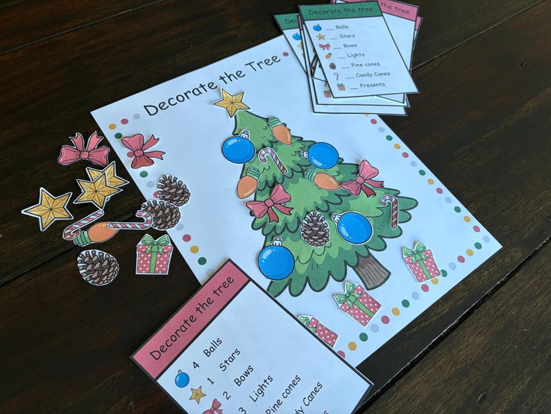 May include: A Christmas-themed activity set with a decorated tree illustration and cut-out decorations. The set includes balls, stars, bows, lights, pine cones, candy canes, and presents. The words "Decorate the Tree" are printed on the page.