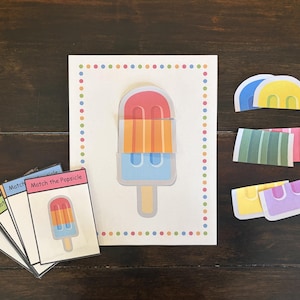 Può includere: Un set di attività di abbinamento di ghiaccioli composto da una carta centrale con un grafico di un ghiacciolo a tre sezioni, una pila di carte di riferimento con la scritta Match the Popsicle e ritagli di carta di segmenti di ghiacciolo.
