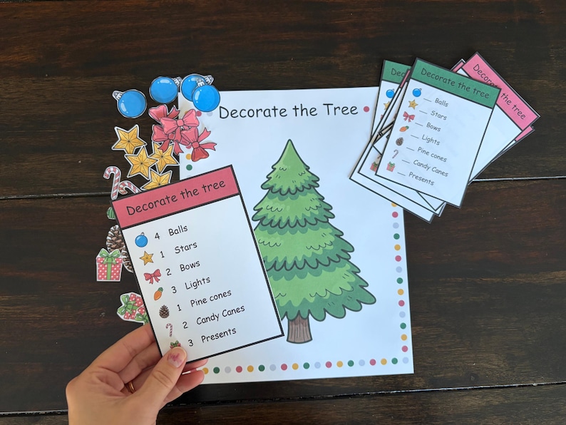 May include: A Christmas-themed activity set with a large illustrated tree, cards, and cutouts of ornaments. The cards list items like balls, stars, and bows. The cutouts include blue balls, gold stars, and red bows.
