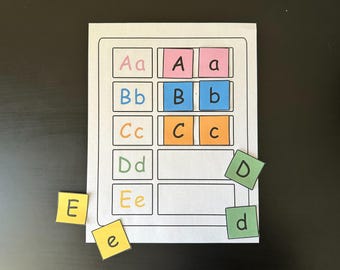 May include: A learning activity sheet with the alphabet. The sheet has boxes with uppercase and lowercase letters A through E. Several letter tiles are scattered around the sheet, including the letters D, d, E, and e. The letters are in various colors.