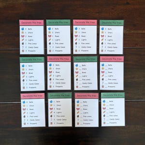 May include: Twelve small cards with the text "Decorate the tree" at the top. Each card has a list of Christmas-themed items like bells, stars, bows, lights, pine cones, candy canes, and presents.
