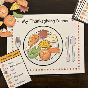 Może przedstawiać: Edukacyjna gra o tematyce Święta Dziękczynienia z talerzem, sztućcami i wycinkami jedzenia. Wyświetlany jest tekst "My Thanksgiving Dinner". Zawiera kartę "Build a dinner plate" z ilustracjami i ilościami jedzenia.