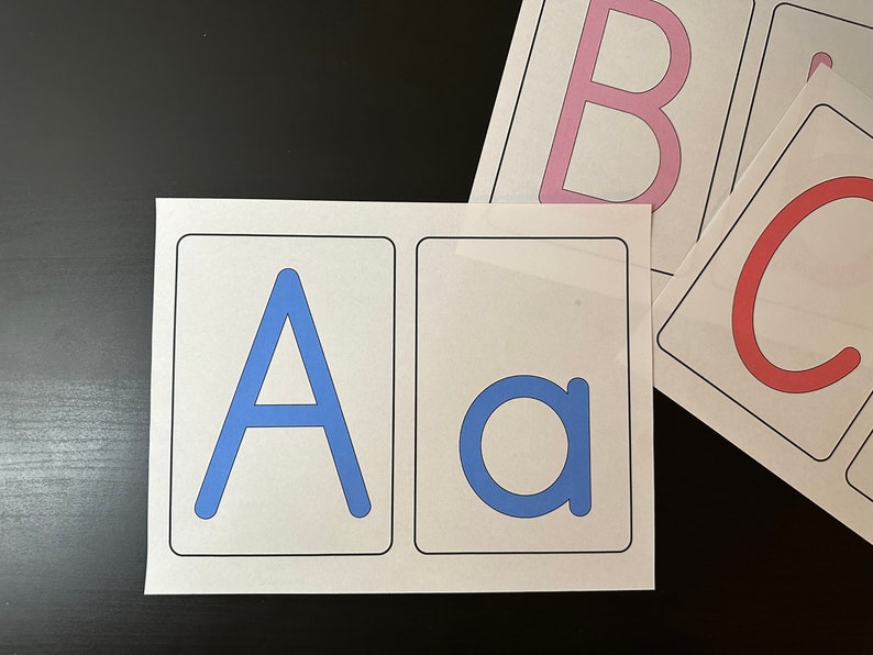 May include: Two white cards with blue letters. The first card has a capital A and the second card has a lowercase a.