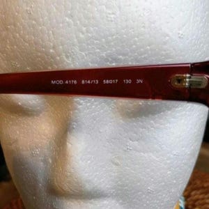 May include: Close-up of the temple of a pair of red eyeglasses. The text "MOD. 4176 814/13 58017 130 3N" is printed in white on the temple. The glasses are set against a white background.