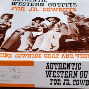 May include: A box featuring a sepia-toned image of children in Western outfits. The box reads "AUTHENTIC WESTERN OUTFITS FOR JR. COWBOYS" and "GENUINE COWHIDE CHAP AND VEST SETS". The box also has a size and style label.