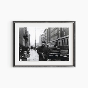 a black and white photo of a man standing on a city street