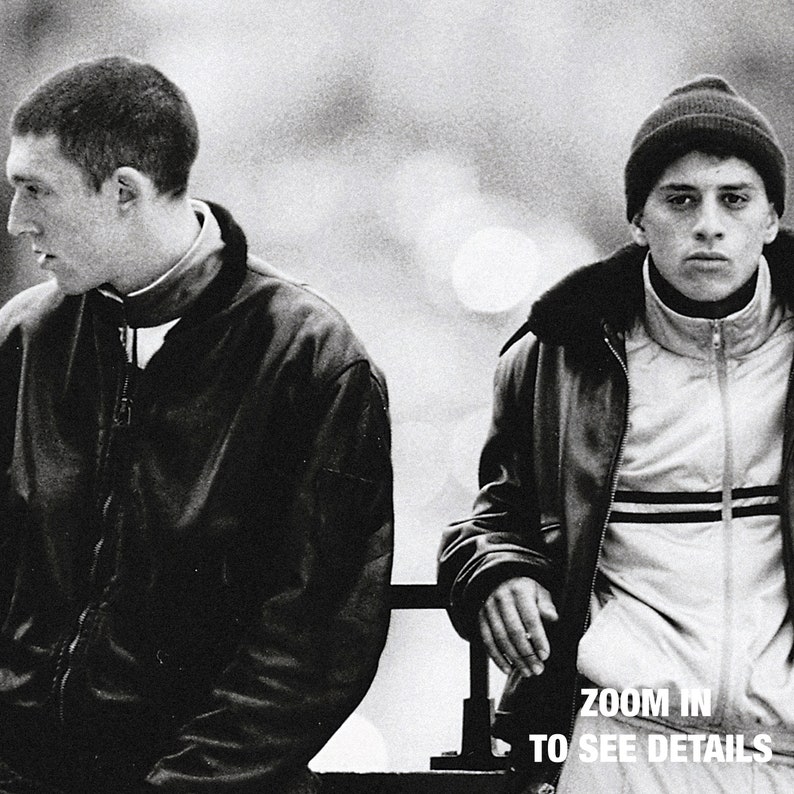 a black and white photo of two men sitting on a bench