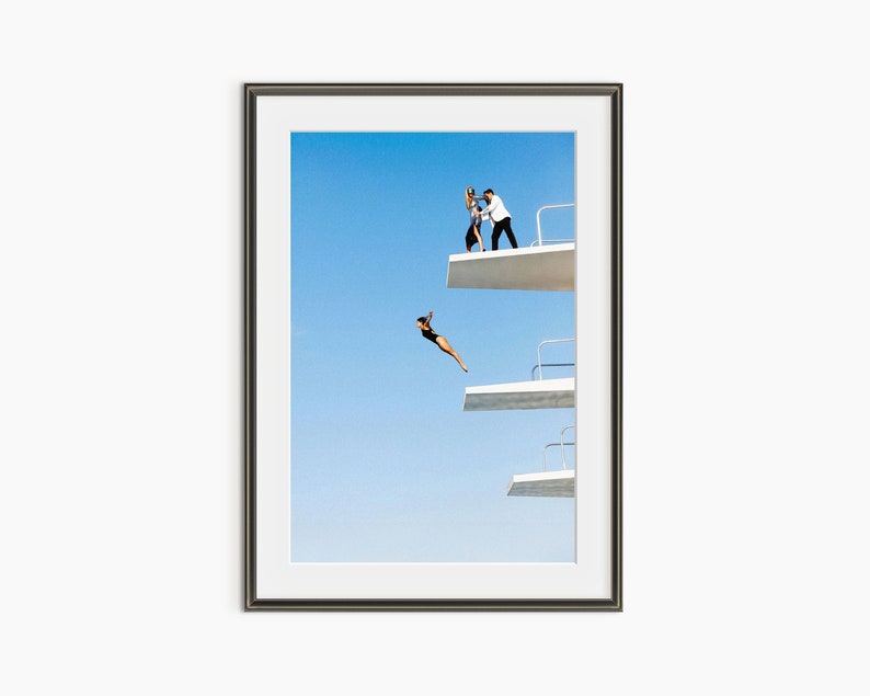 a man standing on the edge of a building while another man flies a kite