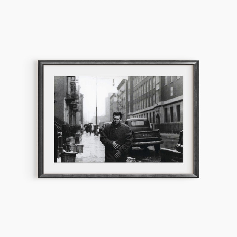 a black and white photo of a man standing on a city street