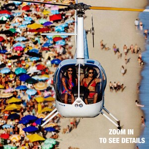 a helicopter flying over a crowded beach with people