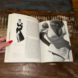 May include: A black and white photo of a woman wearing a white corset. The corset has a low neckline and a fitted bodice. The photo is from a book titled "More Than Skin Deep".