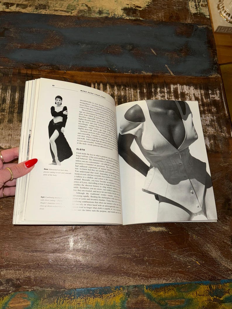 May include: A black and white photo of a woman wearing a white corset. The corset has a low neckline and a fitted bodice. The photo is from a book titled "More Than Skin Deep".