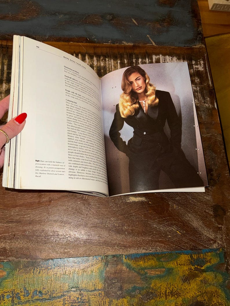 May include: A magazine page open to a spread featuring a woman with long blonde hair wearing a black suit jacket. The text on the page discusses the importance of hair and its role in fashion.