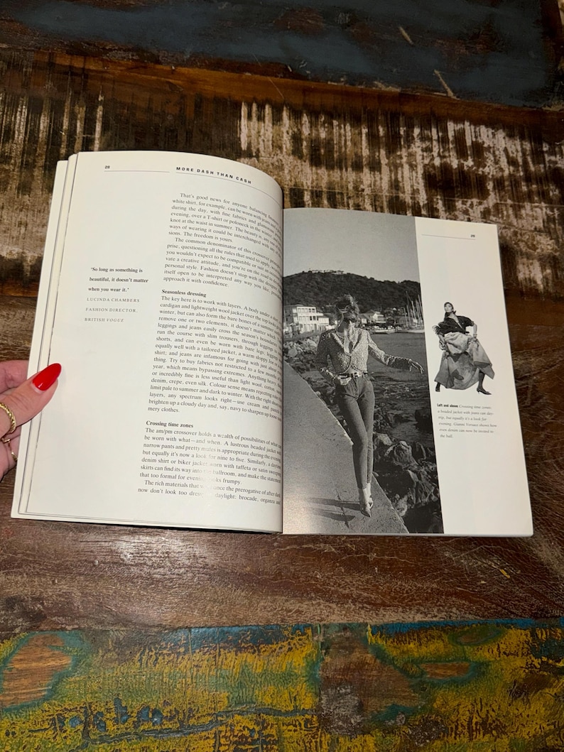 May include: A woman in a blue denim jacket and jeans walks along a rocky shoreline. The text "More Depth Than Cash" is visible on the page.