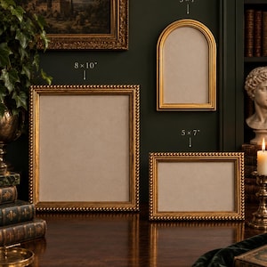 May include: Three gold picture frames with beaded edges. One rectangular frame is 20.32x25.4 cm, one arched frame is 12.7x17.78 cm, and one horizontal rectangular frame is 12.7x17.78 cm. Each frame features a light-coloured mat board interior.
