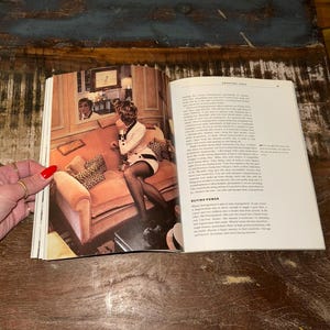 May include: A woman in a white and black dress sits on a pink velvet sofa with leopard print pillows. The sofa is in a room with a mirror reflecting a man in a white shirt. The text on the page reads "Shopping Logic" and "Buying Power".