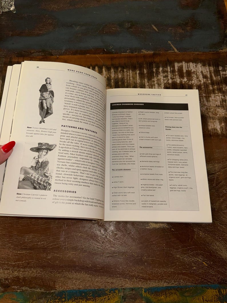 May include: Open book with a white background showing a page with the text "More Cash Than Cash" and a page with the text "Wardrobe Tactics" and "Ludinga Chambers Chooses". The book is open to a page with a black and white illustration of a man in a suit and a page with a black and white illustration of a woman in a dress.
