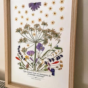 Tableau de fleurs pressées bleues, jaunes et roses dans un cadre en bois clair