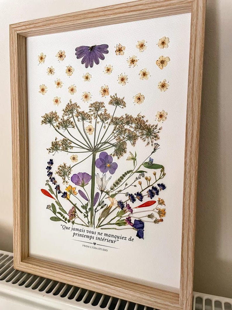 Tableau de fleurs pressées bleues, jaunes et roses dans un cadre en bois clair