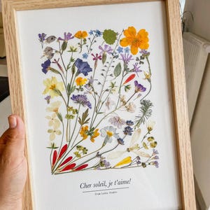 Fleurs jaunes, violettes et blanches pressées, composées dans un cadre en bois clair