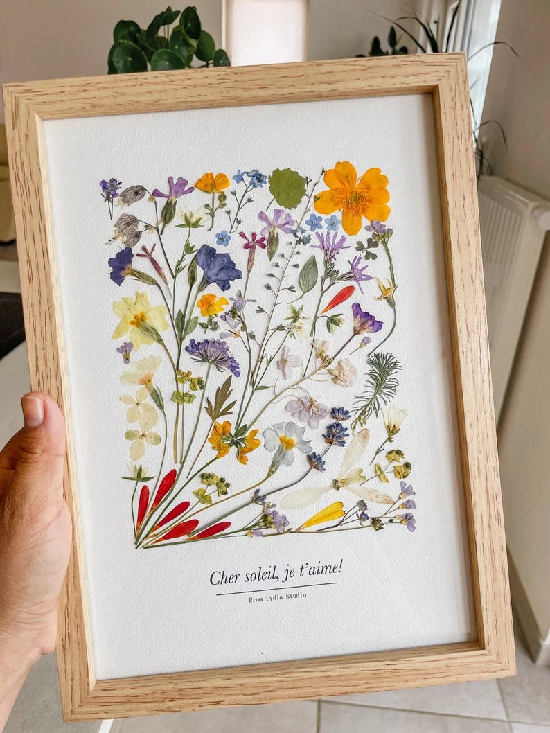 Fleurs jaunes, violettes et blanches pressées, composées dans un cadre en bois clair