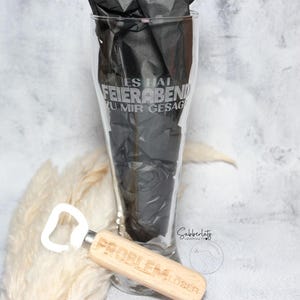 May include: A clear glass beer stein with the text "Es hat Feierabend zu mir gesagt" etched on the side. A wooden bottle opener with the text "Problem?  &Ouml;ffen!" is in the foreground.