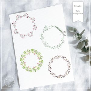 May include: Four watercolor wreath illustrations on a white background. The wreaths are made of green leaves and pink flowers. The text "Zarte Frühlingskränze" is in the top right corner of the image.