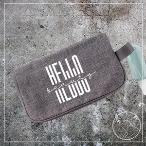 May include: Gray zippered pouch with a white graphic that says "HELLO beauty WORLD".
