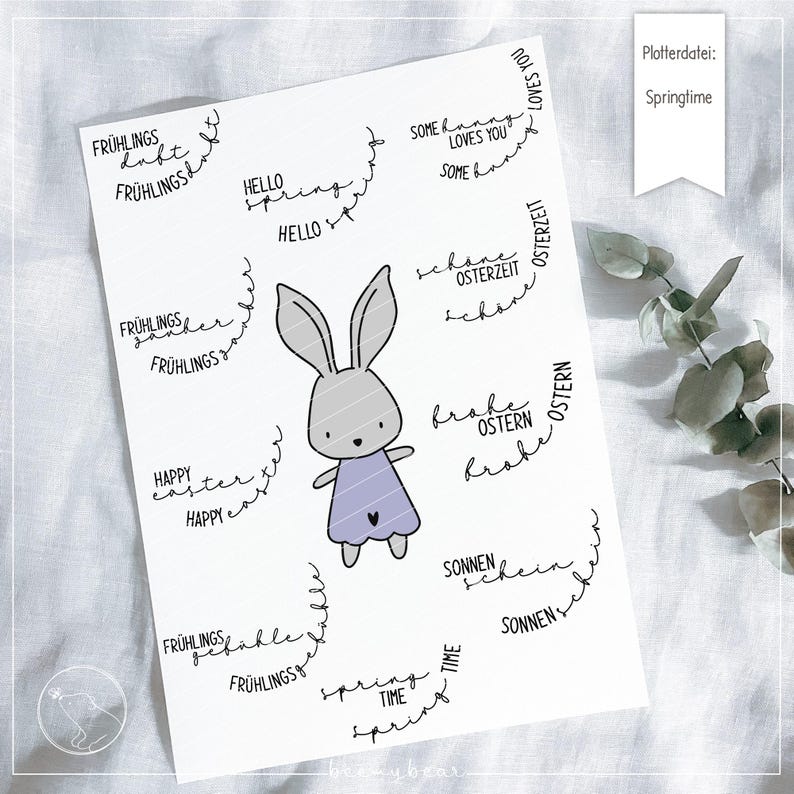 以下が含まれることがあります： かわいいウサギのイラストと、ドイツ語と英語で書かれた春とイースターをテーマにしたさまざまなフレーズが描かれた印刷可能なデザインシート。フレーズには、「Springtime」、「Happy Easter」、「Hello Spring」、「Some bunny loves you」、「Sunshine」、「Fr&uuml;hlingszeit」が含まれています。