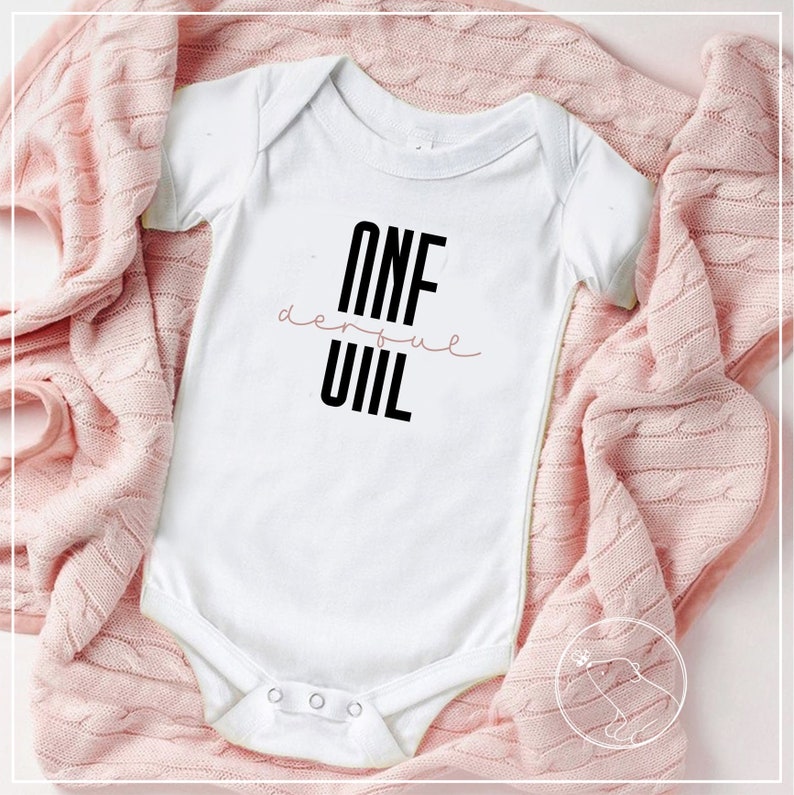 May include: White baby onesie with black text that reads "ONE derful  UIL".