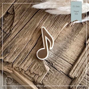 May include: A brown musical note magnet with a white border, set against a rustic wooden background. The magnet has the text "Magnet Note" in a teal box. The image is a close-up shot.