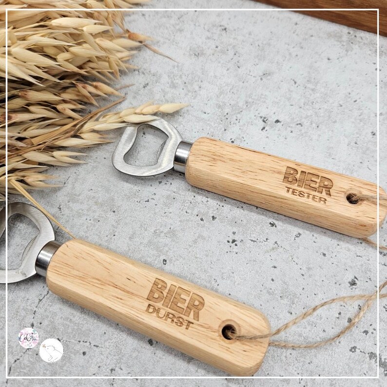 May include: Two wooden bottle openers with metal bottle opener heads. One opener has the text "BIER TESTER" engraved on the wood. The other opener has the text "BIER DURST" engraved on the wood.