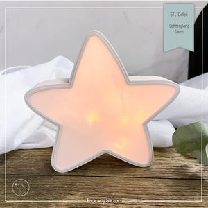 May include: A star-shaped night light with a soft, glowing interior. The light has a white border and a warm, peach-colored glow. The text on the image reads "STL-Datei: Lichterglanz Stern".