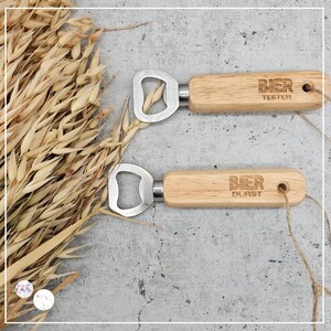 May include: Two wooden bottle openers with metal bottle opener heads. The top opener has the text "BIER TESTER" engraved on the handle. The bottom opener has the text "BIER DURST" engraved on the handle.
