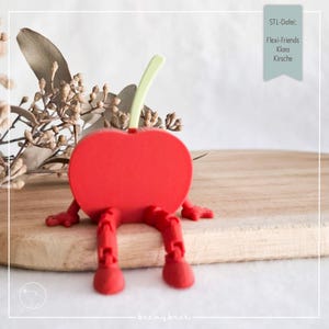 May include: A red cherry-shaped figurine with articulated legs and arms, and a green stem. The figurine is sitting on a wooden surface. Text on the image reads "STL-Datei: Flexi-Friends Klara Kirsche."