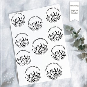 Puede incluir: Ocho pegatinas circulares en blanco y negro con diseños florales y texto en alemán. El texto en las pegatinas incluye frases como "Live your life in full bloom", "The earth laughs in flowers", y "All good things are wild & free".