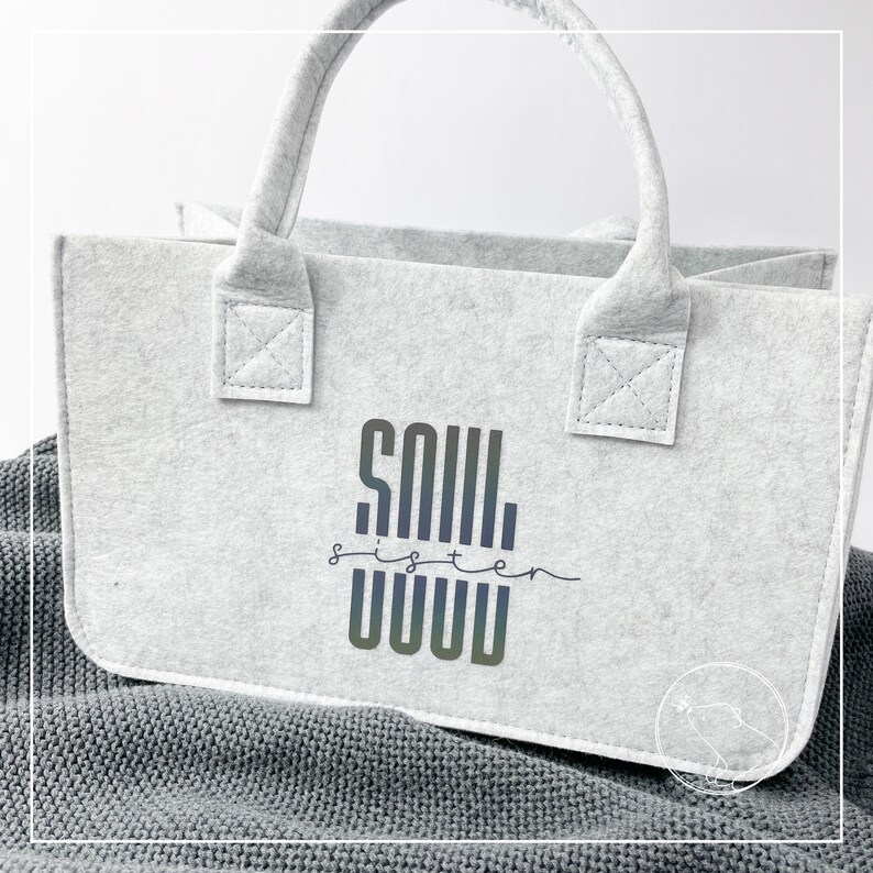 May include: A white felt tote bag with a black and gray graphic that says "Soul Sister" in a stylized font.