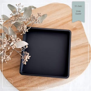 Puede incluir: Una bandeja cuadrada negra sobre una superficie de madera, con acentos florales secos. La bandeja tiene un diseño simple y moderno. El texto en la imagen dice "STL-Datei: Schale Quadrat".