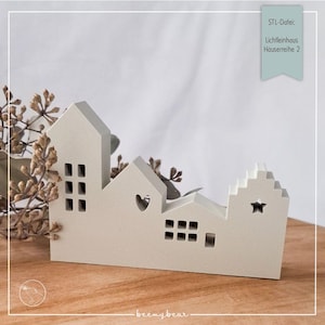Può includere: Un set di tre case in legno dipinte di bianco con finestre ritagliate e dettagli decorativi. Le case sono disposte in fila su una superficie di legno. Il testo "STL-Datei:  Lichtleinhaus  Hausreihe 2" è visibile nell'angolo in alto a destra dell'immagine.