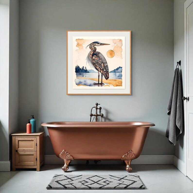 K&ouml;nnte beinhalten: Ein gerahmter Aquarelldruck eines Reihers an einem Strand, mit einer gelben Sonne im Hintergrund. Das Kunstwerk hat ein nat&uuml;rliches, ruhiges Thema. Der Druck wird &uuml;ber einer kupferfarbenen Badewanne mit verzierten F&uuml;&szlig;en ausgestellt, was dem Badezimmer einen Hauch von Eleganz verleiht.