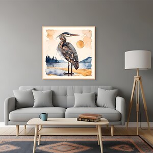 K&ouml;nnte beinhalten: Ein gerahmter Aquarelldruck eines Graureihers, der an einem Strand steht. Das Kunstwerk zeigt eine detaillierte Illustration des Vogels mit einem Sonnenuntergang und Wasser im Hintergrund. Der Reiher ist in Grau-, Blau- und Braunt&ouml;nen dargestellt.