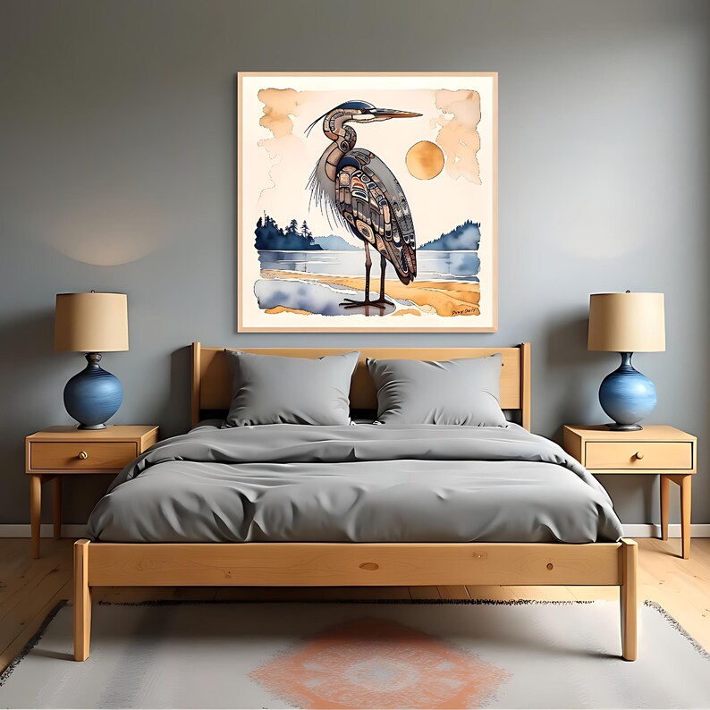 K&ouml;nnte beinhalten: Aquarelldruck eines Graureihers am Strand, mit Sonne und Wasser im Hintergrund. Das Kunstwerk ist in einem hellen Holzrahmen gerahmt und h&auml;ngt &uuml;ber einem Bett mit grauer Bettw&auml;sche. Der Raum hat zwei blaue Lampen auf Nachttischen aus Holz.