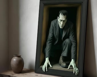 May include: A framed three-dimensional wall art piece featuring a pale green-skinned figure with dark hair, wearing a dark grey suit jacket and trousers, crouching within the frame with hands extending over the bottom edge of the black frame.