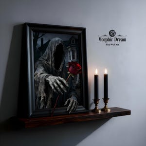 May include: A framed gothic art print depicts a robed figure holding a red rose. The artwork is displayed on a dark wooden shelf, accompanied by two black candles in brass holders. The text "Morphic Dream Fine Wall Art" is visible.